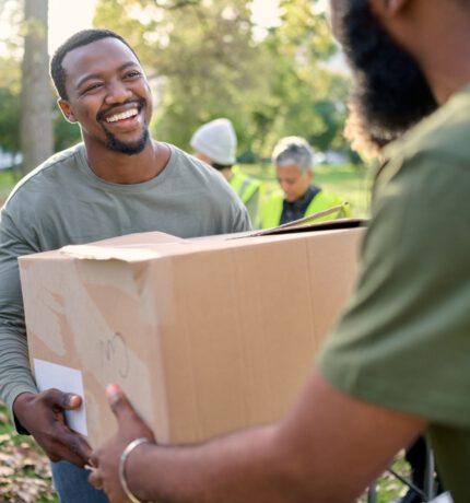 Black,Man,,Volunteering,And,Giving,Box,In,Park,Of,Donation,
